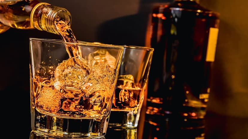 canadian whiskey being poured into a glass with ice in a bar